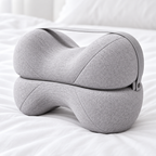 Coussin entre les genoux pliable gris posé sur un lit