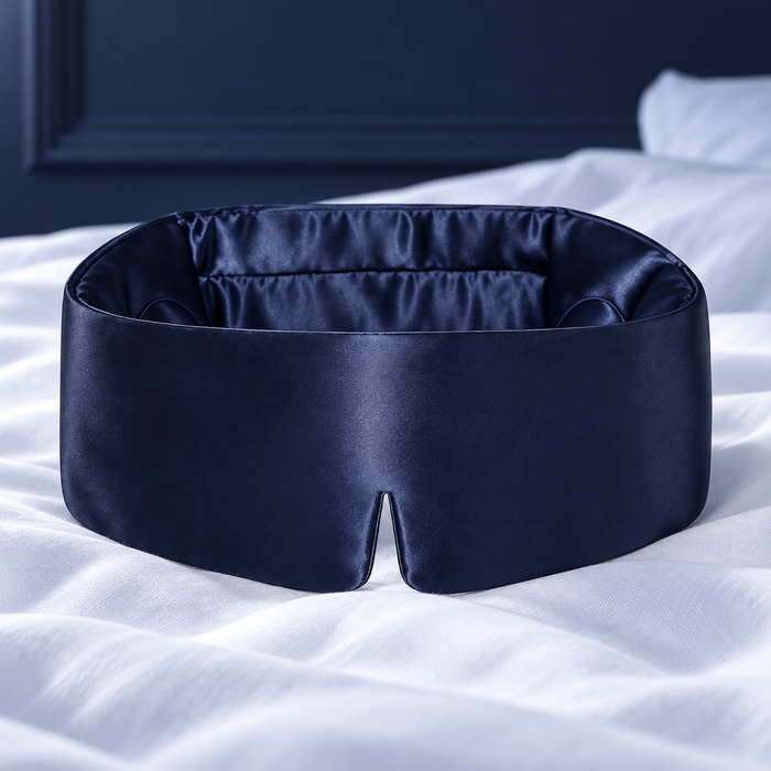 Masque de nuit en soie bleu marine posé sur un lit